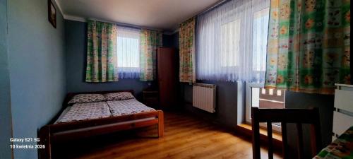 a small bedroom with a bed and two windows at Noclegi u Danuty in Groń