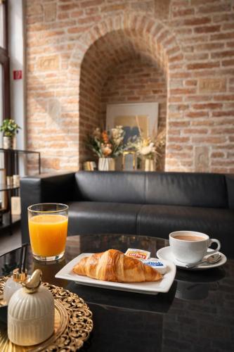 ein Tisch mit einem Teller Brot und einer Tasse Orangensaft in der Unterkunft Saint Michael Boutique & Garni Hotel Trnava in Trnava