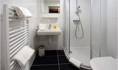 a white bathroom with a shower and a sink at AIS Center in Wolfsberg