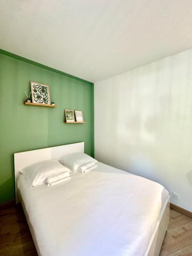 a bedroom with a white bed with a green wall at Le Nid du Petit-Quevilly in Le Petit-Quevilly