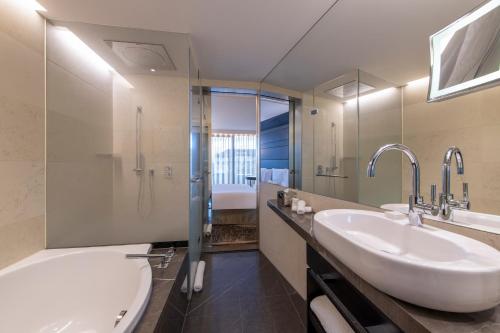a bathroom with a tub and a sink and a shower at Royal Savoy Hotel & Spa in Lausanne