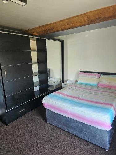a bedroom with a bed and a black cabinet at Bethel Cottage in Oulton