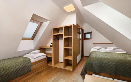 a attic bedroom with two beds and a window at Majláthova Chata Popradské Pleso in Vysoké Tatry