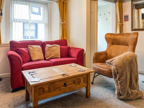 a living room with a red couch and a chair at North Lakes Town House in Penrith