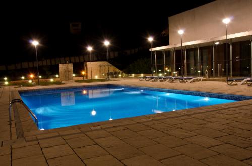 a swimming pool in front of a building at night at VIP Executive Santa Iria Hotel in Santa Iria da Azóia