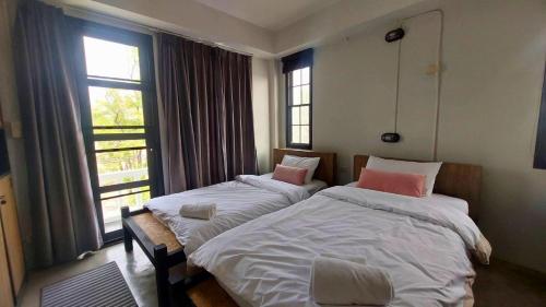 two beds in a room with two windows at Flow Garden Residence in Chiang Mai