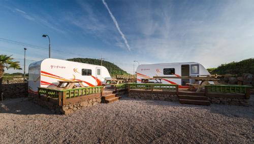 due camper parcheggiati uno accanto all'altro in un parcheggio di Red Windmill Pension a Jeju