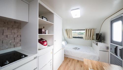 a small kitchen with white cabinets and a window at Red Windmill Pension in Jeju