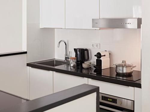 a kitchen with white cabinets and a black counter top at YAYS Amsterdam Salthouse Canal by Numa in Amsterdam