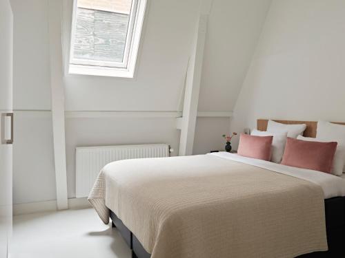 a white bedroom with a large bed with pink pillows at YAYS Amsterdam Salthouse Canal by Numa in Amsterdam