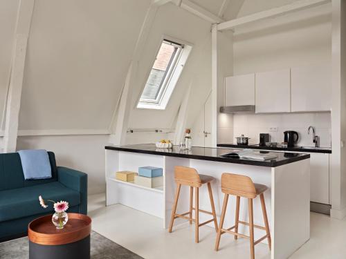 a kitchen and living room with a counter and stools at YAYS Amsterdam Salthouse Canal by Numa in Amsterdam
