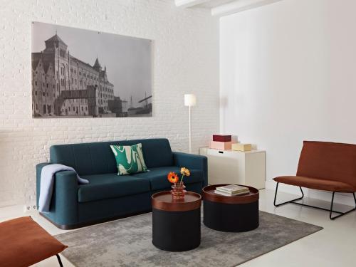 a living room with a blue couch and a table at YAYS Amsterdam Salthouse Canal by Numa in Amsterdam