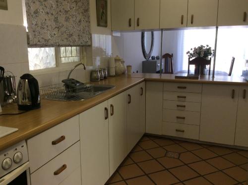 a kitchen with white cabinets and a sink at On Broadwalk Cottage in Cape Town