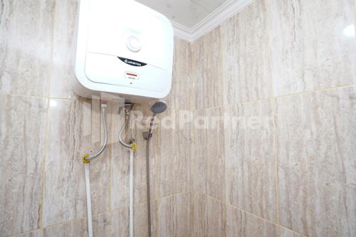 a shower in a bathroom with a hair dryer on the wall at Griya Poerwoto Syariah near Pasar Klewer Solo RedPartner in Solo