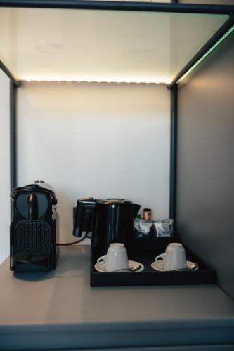 a shelf with two mugs and a coffee maker at Amario Suites Hotel in Aigio