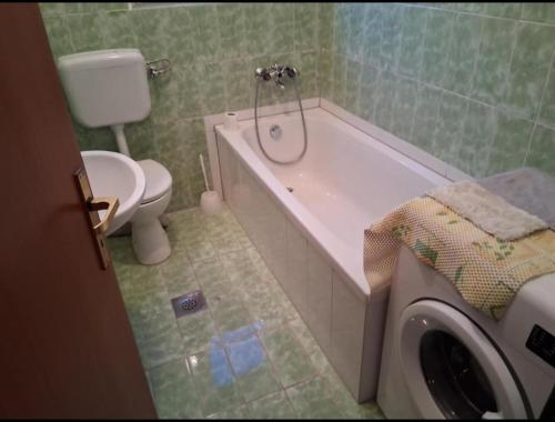 a bathroom with a tub and a toilet and a washing machine at Elma in Kampor