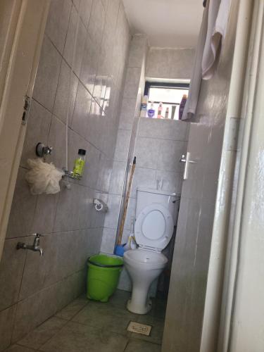 a bathroom with a toilet and a green bucket at Royal suburbs tsavo in Nairobi