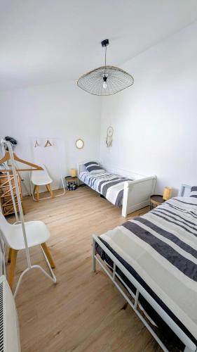 una camera da letto con due letti, un tavolo e una sedia di Maison cosy a Plobannalec-Lesconil