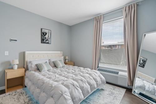 a white bedroom with a large bed and a window at Valclyde Elevated Urban Haven in Minneapolis