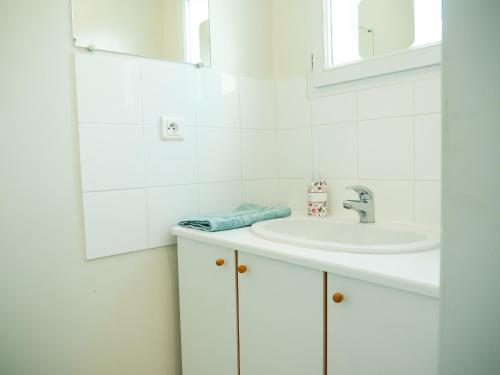 a white bathroom with a sink and a mirror at L'ESCAPADE T3 avec terrasse privative in Lussac-les-Châteaux