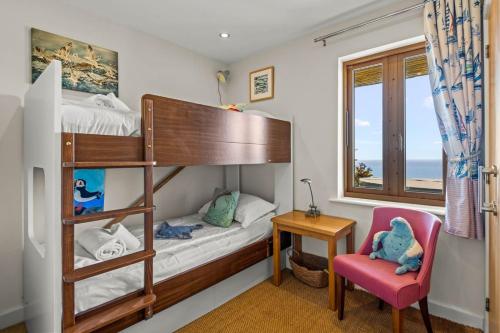 a bedroom with a bunk bed and a chair at House 43 in Looe