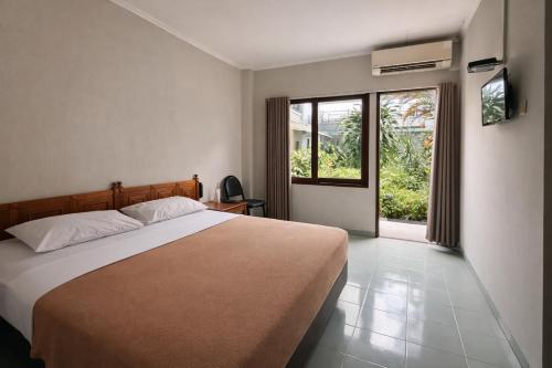 a bedroom with a large bed and a window at Hotel Winotosastro Garden in Yogyakarta