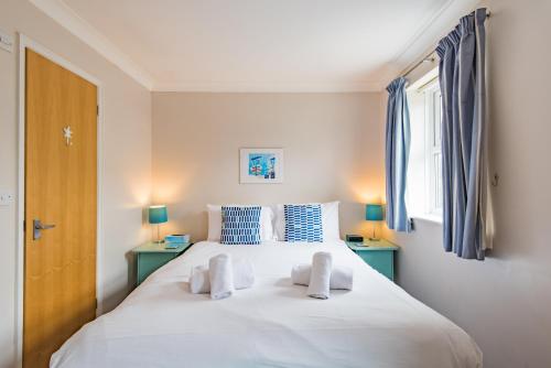 a bedroom with a large white bed with blue accents at Gerald's Place in Deal