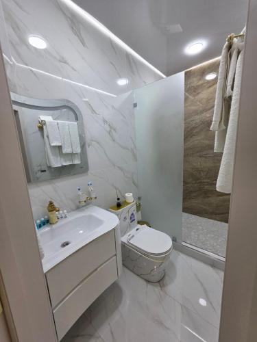 a white bathroom with a toilet and a sink at Old City Samarkand Hotel in Samarkand