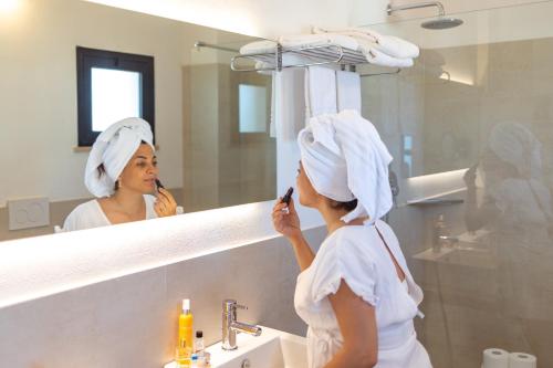 a woman brushing her teeth in front of a mirror at Hotel Tiffany & Resort in Cesenatico