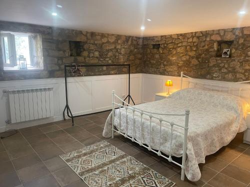 a bedroom with a bed and a stone wall at Casa Borboleta in Chão de Lamas