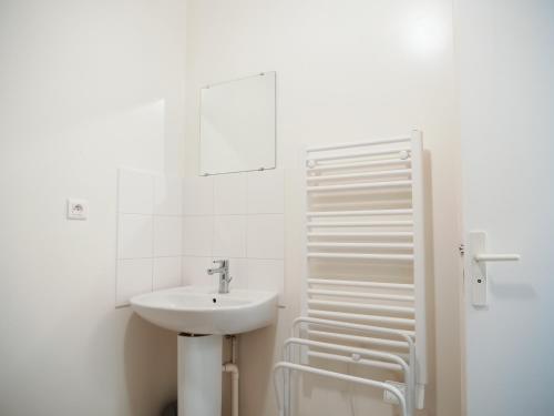 a white bathroom with a sink and a mirror at LE REPOS DU VOYAGEUR T3 45 m2 tout confort in Lussac-les-Châteaux