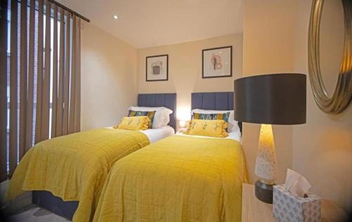 two beds with yellow sheets in a bedroom at Westminster two bed one bath sleeps 5 with Air-Con in London