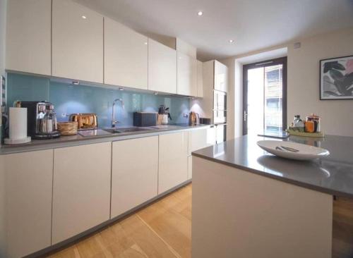 a kitchen with white cabinets and a black counter top at Westminster two bed one bath sleeps 5 with Air-Con in London