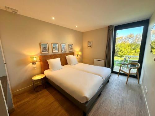 a bedroom with a large bed and a large window at Best Western Hotel de la plage Normandie in Asnelles