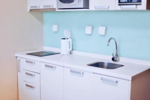 a white kitchen with a sink and a counter top at Pumpkin Hotel in Beijing