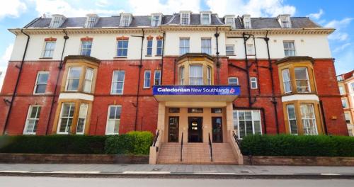 a red brick building with a blue sign on it at The Caledonian New Southlands Hotel in Scarborough