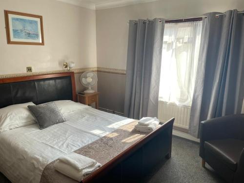 a bedroom with a bed and a chair and a window at The Bell Hotel in Mildenhall