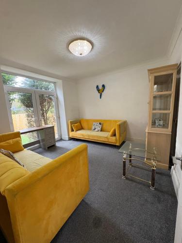 a living room with two yellow couches and a table at Mountain Ash Cottage in Mountain Ash