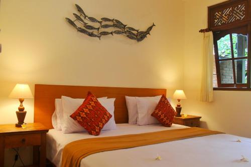 a bedroom with a bed with two lamps and a fish on the wall at Tara House in Ubud