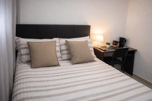 a bed with two pillows and a desk in a room at Sunlit Retreat Private Flatlet with Solar Power Pool Fast WiFi & Secure Parking in Roodepoort
