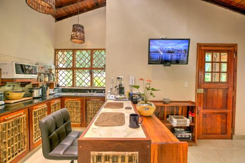 a kitchen with a table and a tv on the wall at Uva Blue Villas - Zen Villa 1 - 3 Bedroom Villa, Private Garden & Yoga Deck in Puerto Viejo