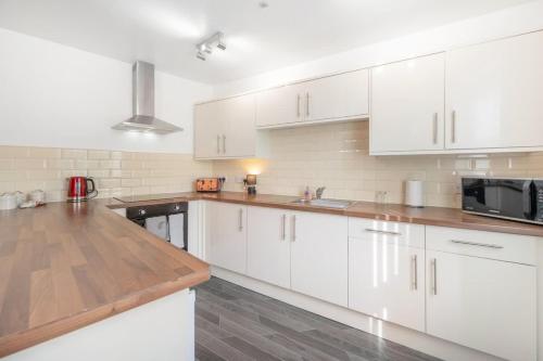 a kitchen with white cabinets and a wooden counter top at NEW! Stylish 5-Bed Apartment in Stockton-on-tees by Stay With Us, Perfect for Contractors & Large Groups, FREE Parking! in Thornaby on Tees