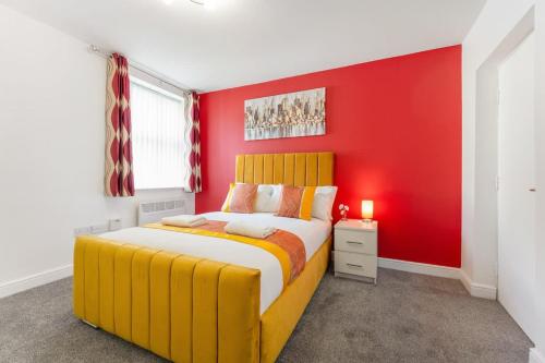 a bedroom with a yellow bed and a red wall at NEW! Stylish 5-Bed Apartment in Stockton-on-tees by Stay With Us, Perfect for Contractors & Large Groups, FREE Parking! in Thornaby on Tees