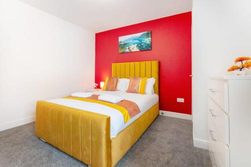 a bedroom with a large bed with a red wall at NEW! Stylish 5-Bed Apartment in Stockton-on-tees by Stay With Us, Perfect for Contractors & Large Groups, FREE Parking! in Thornaby on Tees