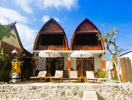 a building with chairs and umbrellas in front of it at Sandy Beach Villas in Toyapakeh