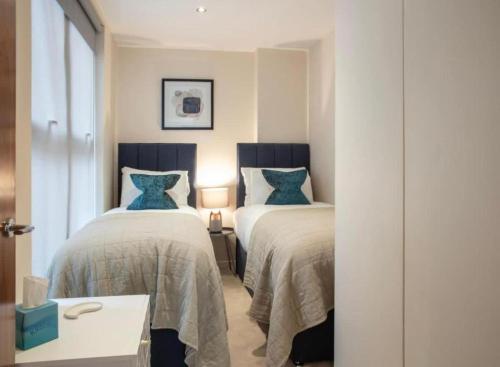 a bedroom with two beds with blue pillows at Westminster 2 bed 2 bath apartment with Air-Con in London