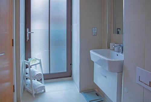 a white bathroom with a sink and a shower at Westminster 2 bed 2 bath apartment with Air-Con in London