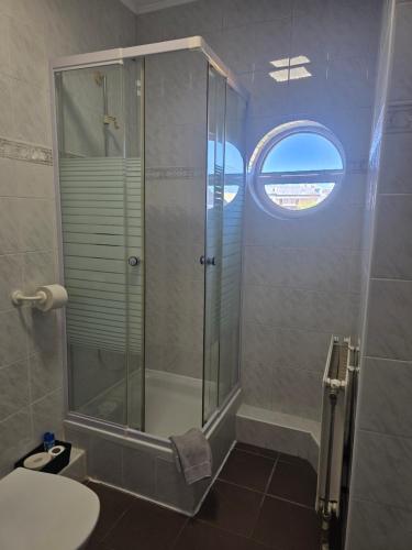 a bathroom with a shower and a toilet and a window at Király Szálló in Nagykanizsa