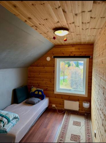 a bedroom in a log cabin with a bed and a window at Spacious seaside apartment with balcony in Sorreisa