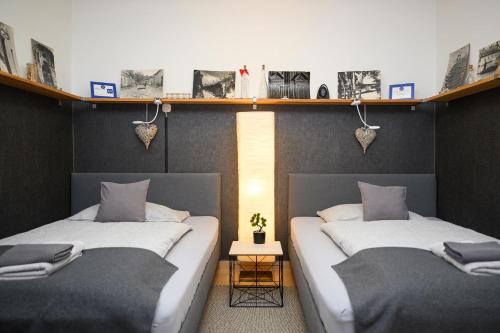 two beds in a room with shelves on the wall at Borálom Stúdió Apartman Tokaj in Tokaj